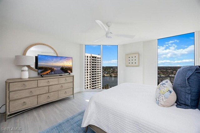 bedroom with ceiling fan, floor to ceiling windows, and light wood-type flooring