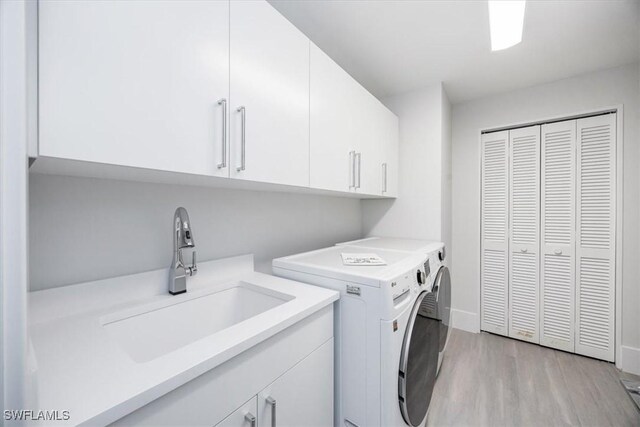 washroom with cabinets, independent washer and dryer, light hardwood / wood-style floors, and sink