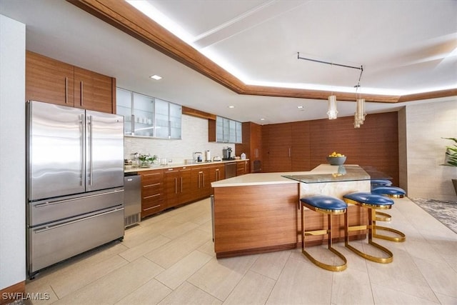 kitchen featuring hanging light fixtures, a kitchen breakfast bar, backsplash, a kitchen island, and appliances with stainless steel finishes