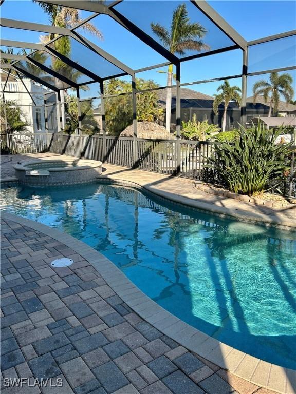 view of pool featuring glass enclosure, an in ground hot tub, and a patio area