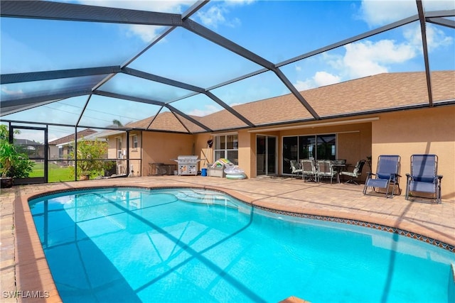 view of pool with glass enclosure and a patio area