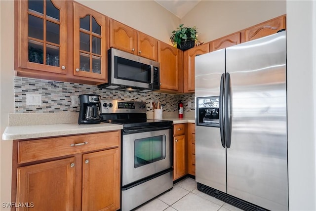 kitchen with appliances with stainless steel finishes, backsplash, and light tile patterned floors