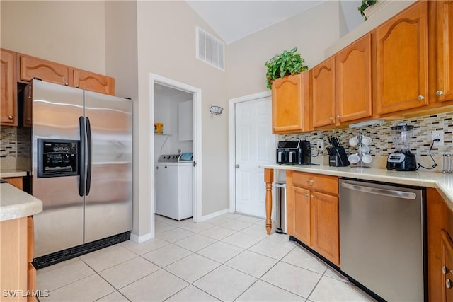 kitchen featuring separate washer and dryer, high vaulted ceiling, decorative backsplash, light tile patterned flooring, and appliances with stainless steel finishes