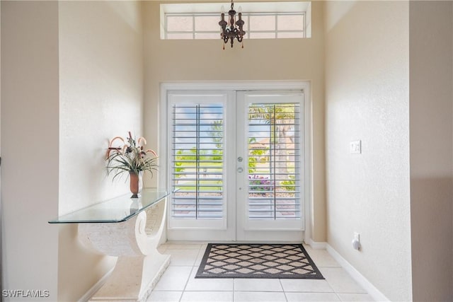 entryway featuring a notable chandelier, light tile patterned floors, and french doors