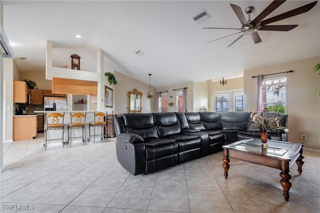 tiled living room with ceiling fan with notable chandelier and lofted ceiling