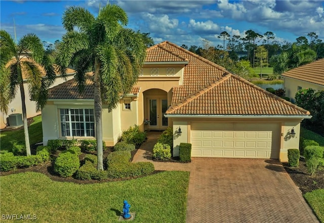 mediterranean / spanish-style home with central AC, french doors, a front yard, and a garage