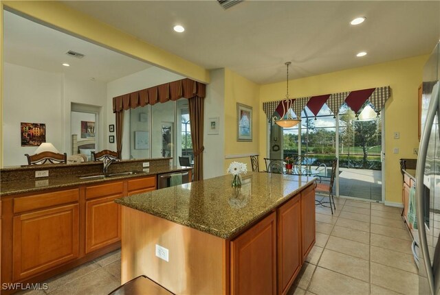 kitchen featuring pendant lighting, a center island, dark stone counters, sink, and light tile patterned flooring