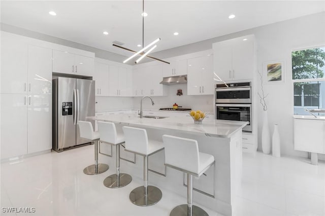 kitchen featuring white cabinets, appliances with stainless steel finishes, an island with sink, and sink