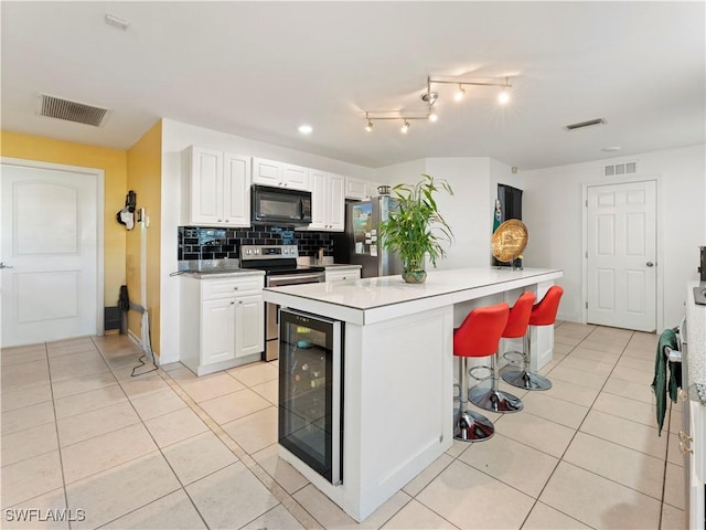 kitchen featuring a center island, white cabinets, wine cooler, appliances with stainless steel finishes, and tasteful backsplash