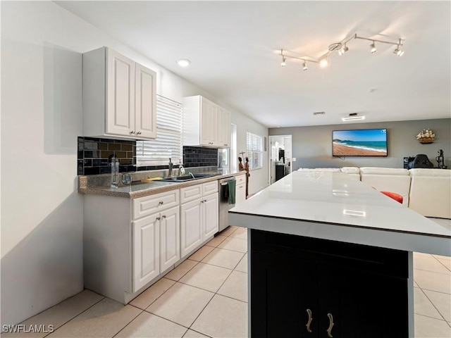 kitchen with dishwasher, sink, a kitchen island, tasteful backsplash, and white cabinets