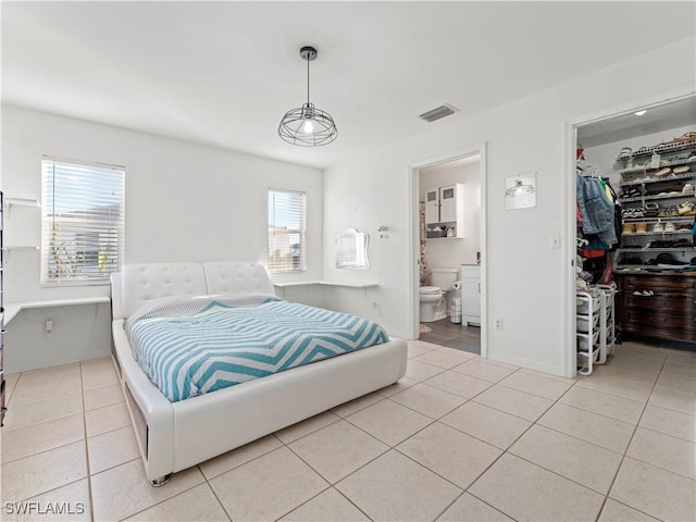 tiled bedroom with a walk in closet, ensuite bathroom, and a closet