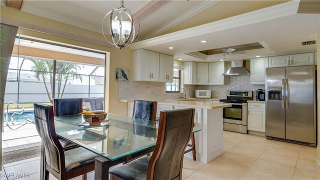 tiled dining space with ornamental molding, ceiling fan with notable chandelier, a tray ceiling, vaulted ceiling, and sink