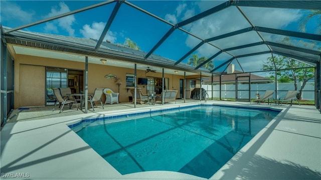 view of pool with ceiling fan, a lanai, and a patio