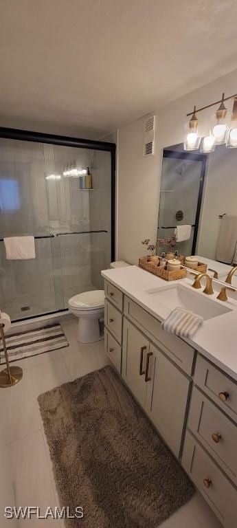 bathroom with tile patterned floors, vanity, toilet, and a shower with shower door