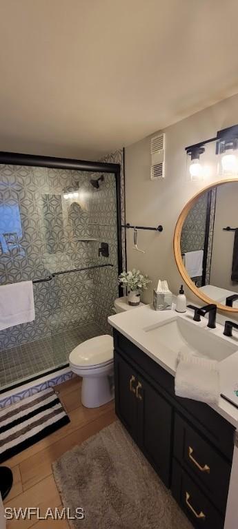 bathroom with toilet, an enclosed shower, and vanity