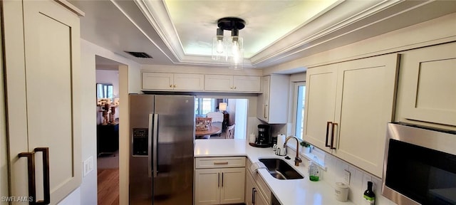 kitchen with hanging light fixtures, white cabinetry, sink, and stainless steel appliances