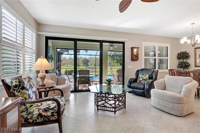 tiled living room with a wealth of natural light and ceiling fan with notable chandelier