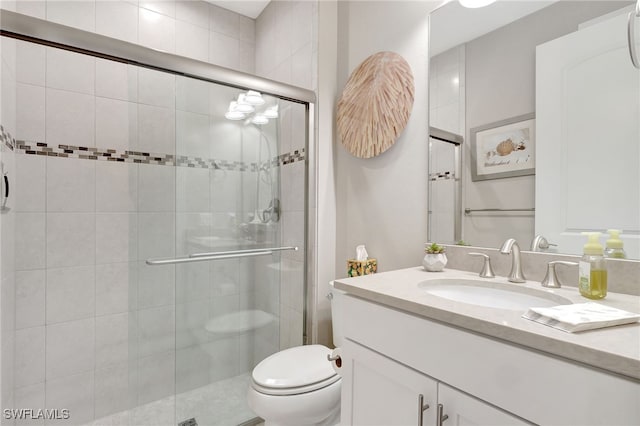 bathroom with vanity, toilet, and a shower with door