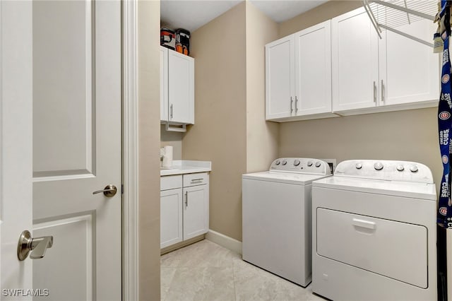 laundry room with cabinets, light tile patterned floors, and washer and dryer