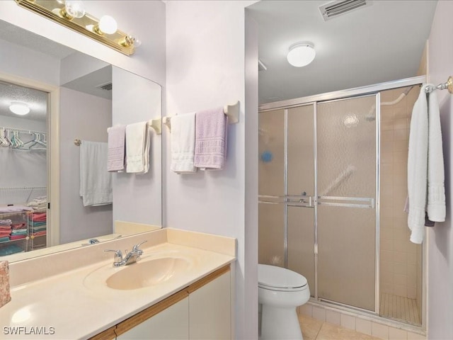 bathroom featuring tile patterned flooring, vanity, an enclosed shower, and toilet