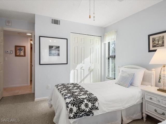 carpeted bedroom with a textured ceiling and a closet