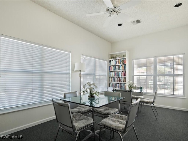 dining space with ceiling fan, dark carpet, and a textured ceiling