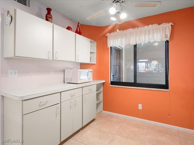 kitchen featuring white cabinets, light tile patterned floors, and ceiling fan