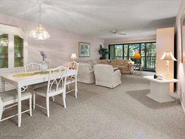 carpeted dining area with ceiling fan with notable chandelier