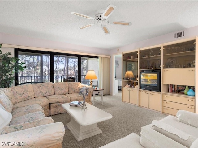 carpeted living room featuring ceiling fan and a textured ceiling