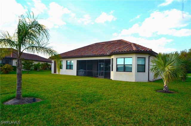 back of property featuring a sunroom and a lawn