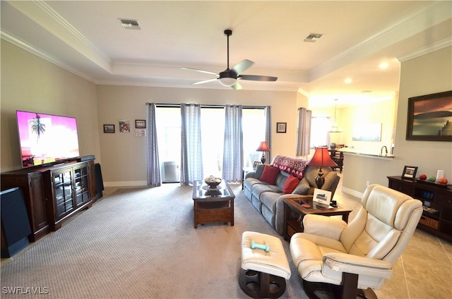 living room featuring a tray ceiling, ceiling fan, and ornamental molding