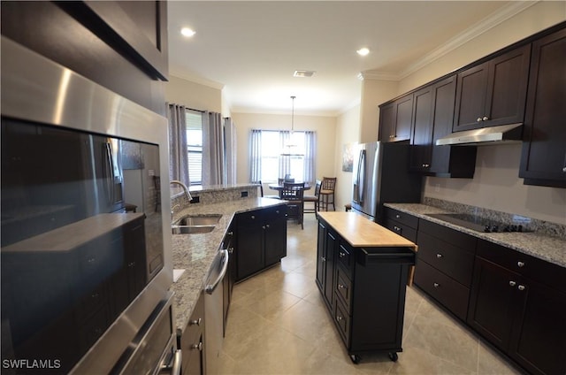 kitchen with light stone countertops, ornamental molding, stainless steel appliances, sink, and hanging light fixtures