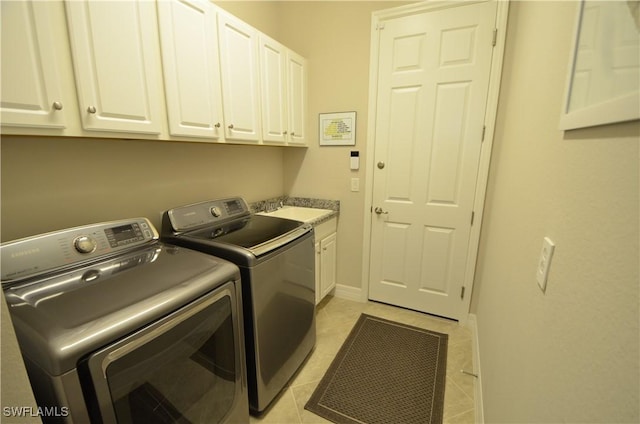 laundry room with cabinets, independent washer and dryer, light tile patterned floors, and sink