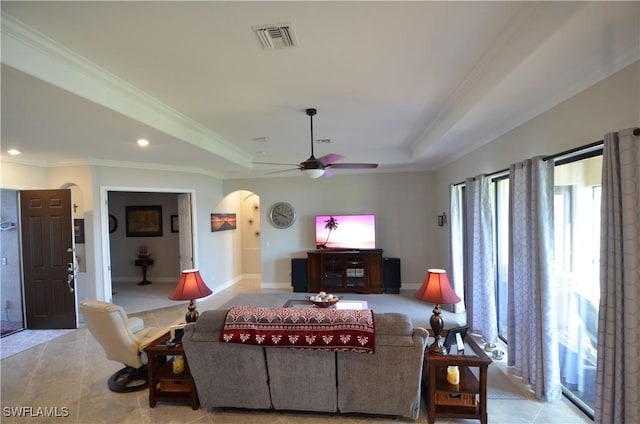 living room featuring light tile patterned floors, a tray ceiling, ceiling fan, and crown molding