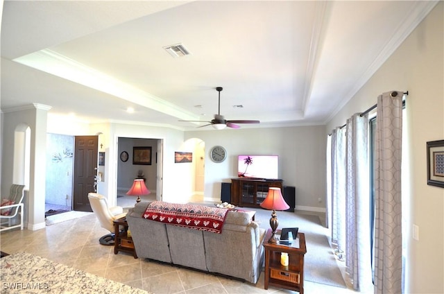 tiled living room with a raised ceiling, ceiling fan, and crown molding