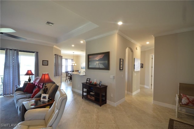 tiled living room with ceiling fan and crown molding