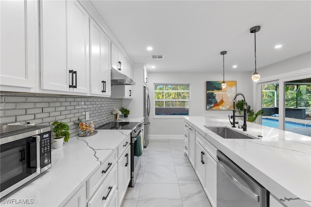 kitchen featuring white cabinetry, appliances with stainless steel finishes, decorative backsplash, decorative light fixtures, and sink