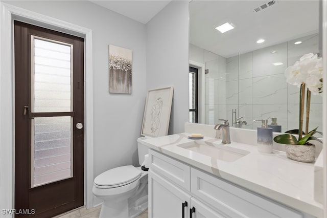 bathroom featuring a shower with door, toilet, and vanity