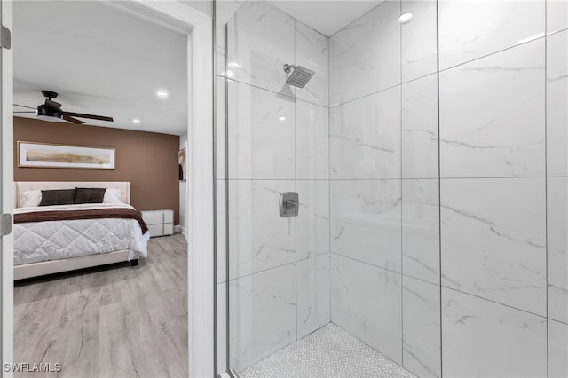 bathroom featuring ceiling fan, hardwood / wood-style floors, and a tile shower