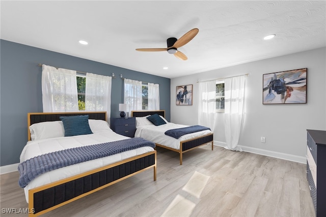 bedroom featuring ceiling fan, light wood-type flooring, and multiple windows