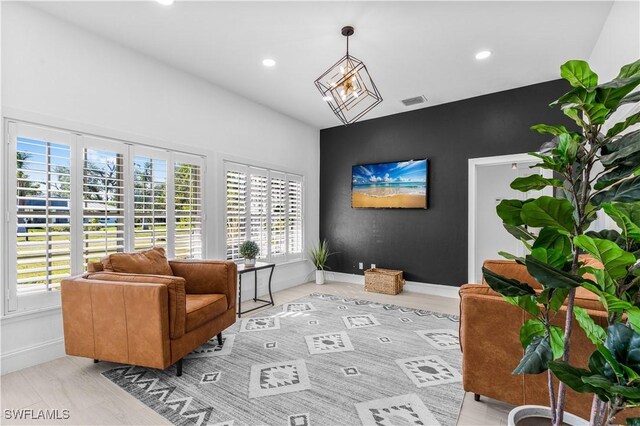 living area with baseboards, visible vents, an accent wall, an inviting chandelier, and recessed lighting