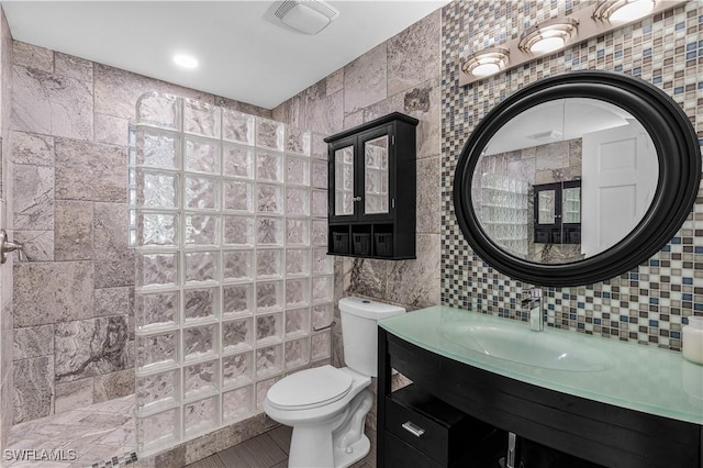 bathroom with toilet, visible vents, vanity, tile walls, and decorative backsplash