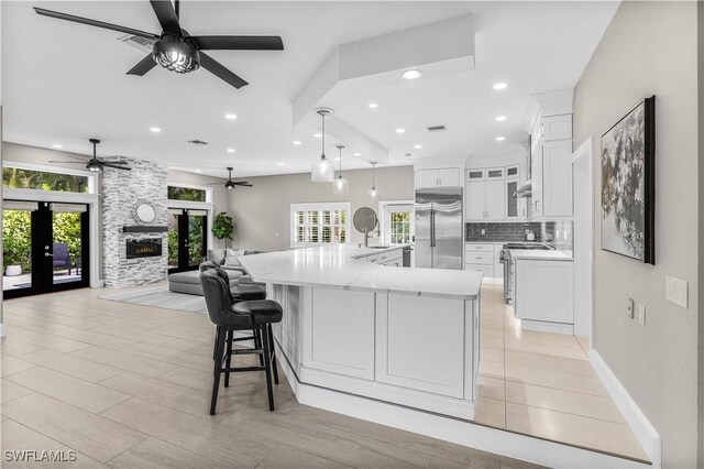 kitchen with hanging light fixtures, white cabinetry, appliances with stainless steel finishes, and a large island with sink