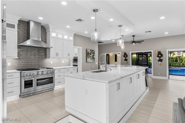 kitchen with a center island with sink, glass insert cabinets, wall chimney range hood, double oven range, and a sink