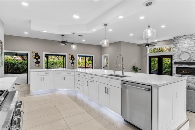 kitchen with stainless steel appliances, a sink, white cabinets, open floor plan, and hanging light fixtures