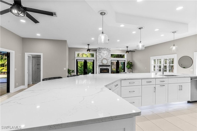 kitchen featuring open floor plan, hanging light fixtures, light stone counters, and white cabinetry