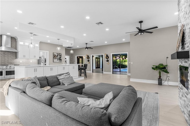 living area with a fireplace, recessed lighting, visible vents, light wood-style flooring, and ceiling fan