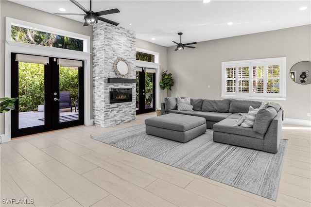 living room featuring a healthy amount of sunlight, ceiling fan, and a stone fireplace