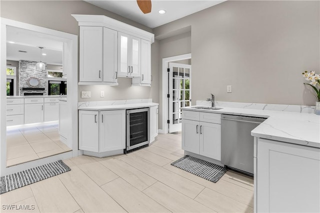 kitchen featuring plenty of natural light, beverage cooler, white cabinets, dishwasher, and a sink