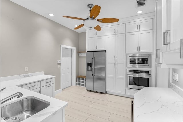 kitchen with light stone counters, appliances with stainless steel finishes, visible vents, and white cabinets